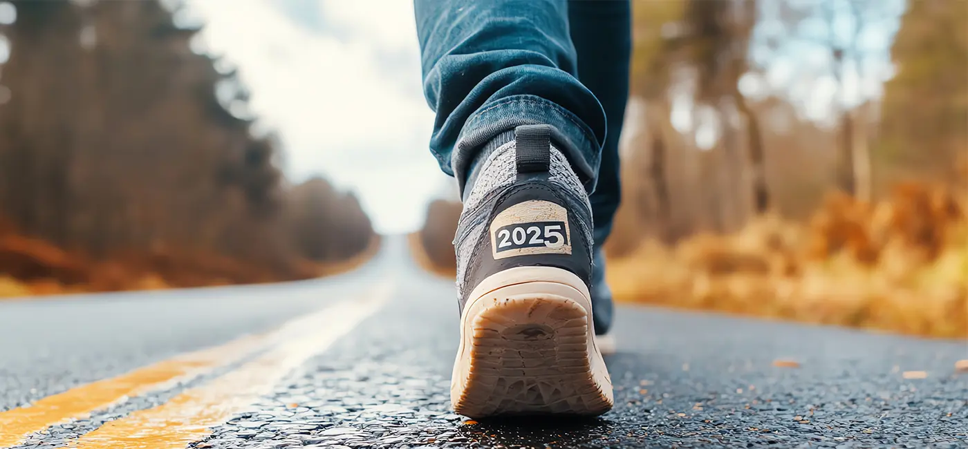 Close up of legs walking on a road, back of trainer labelled with 2025