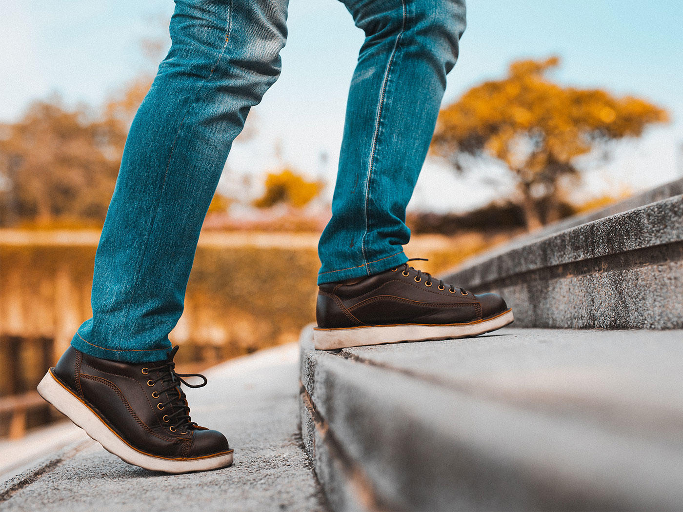 Personne à l'extérieur en jeans et chaussures marron, montant pas.