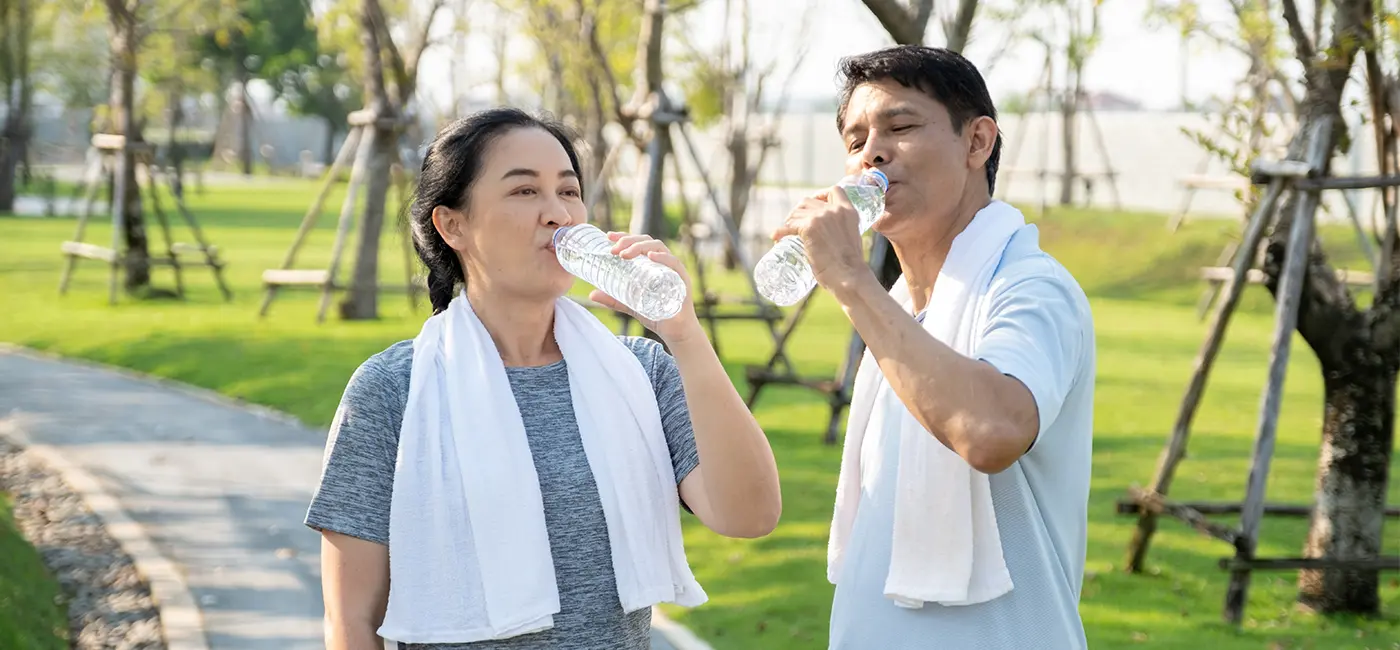 Couple out on a run in a park, they've stopped to drink water