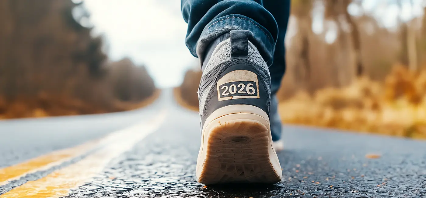 Close up of legs walking on a road, back of trainer labelled with 2026
