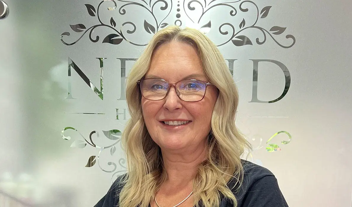 Portrait of Lorraine in her salon smiling at the camera 