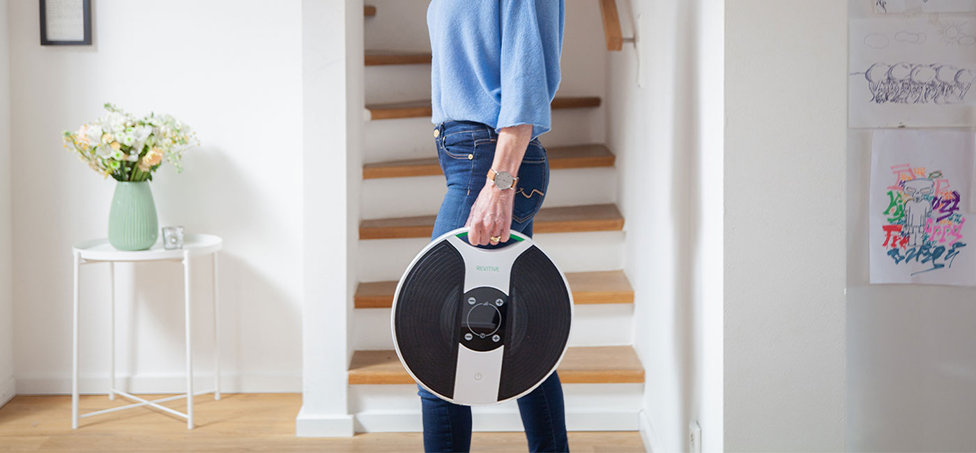Image of Ulrike holding her Revitive medic walking through her house