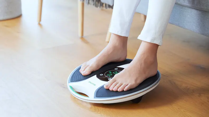 Medic in use image, woman sat in her living room with her feet on the device