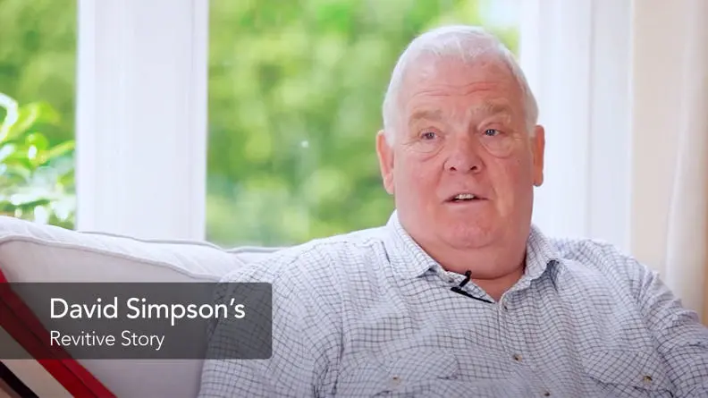 David a Revitive customer sat on his sofa looking at the camera